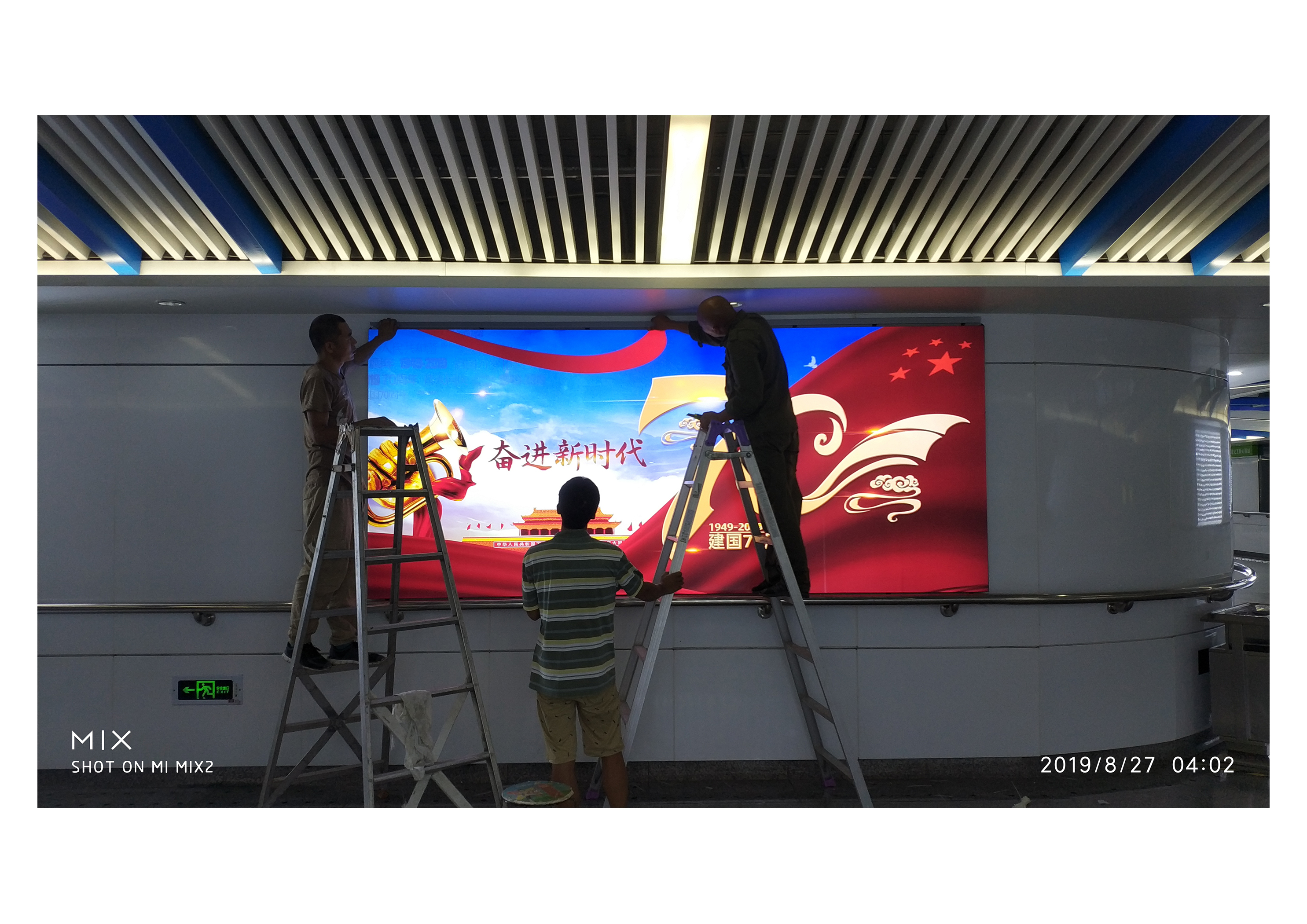 安装人员在公共空间灯箱点位进行画面安装